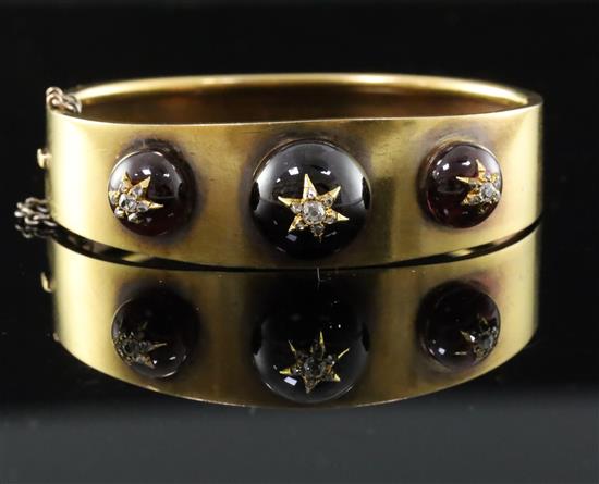 A Victorian gold, three graduated cabochon garnet and diamond set hinged bracelet, gross 29 grams.